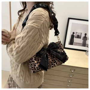 Dettaglio borsa leopardata con grande fiocco in raso nero e tracolla arricciata