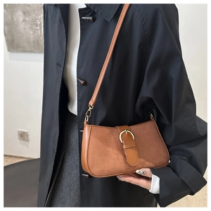 Close-up of brown suede and smooth leather shoulder bag with elegant gold buckle hardware