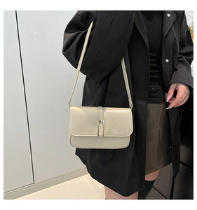 Details einer minimalistischen beige Baguette-Tasche mit Metallschnalle und Lederriemen