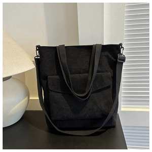 Dettaglio ravvicinato di una borsa tote in velluto nero con tasca e tracolla regolabile