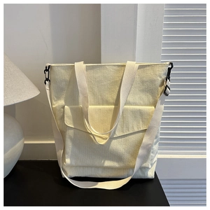 Dettaglio borsa tote in velluto a coste crema con tracolla regolabile e tasca frontale