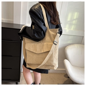 Detail of beige corduroy tote bag featuring a front flap pocket and adjustable strap