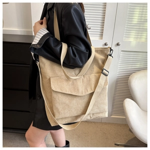 Detail of beige corduroy tote bag showing textured stripes and adjustable crossbody strap