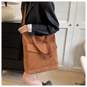 Detailed view of brown corduroy tote bag featuring front flap pocket and webbed straps