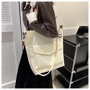 Detail of cream corduroy tote bag featuring front flap pocket and adjustable strap
