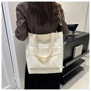 Dettaglio della borsa tote in velluto a coste crema con tasca frontale e tracolla regolabile