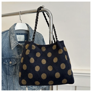 Detail of dark blue tote bag with gold polka dots and sturdy black braided handles