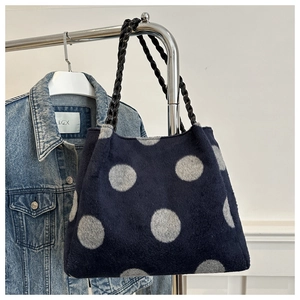 Detail of blue knitted tote bag with gray dots and black braided leather handles