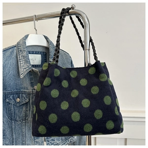 Detail of blue suede tote bag with green polka dots and woven black leather handle