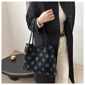 Close-up of stylish tote bag with green polka dots and black woven handles