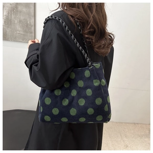 Detail showing high-capacity navy tote bag with green polka dots and woven chain strap