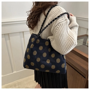 Detail of blue tote bag featuring large brown polka dots and black braided rope handles