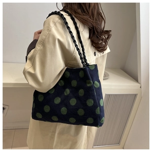 Polka dot tote bag in navy with green circles featuring black chain strap on model shoulder