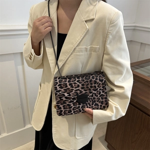 Vintage leopard print shoulder bag with black metal chain and flap closure on a model