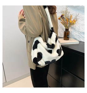Detailansicht der flauschigen schwarz-weißen Plüschtasche mit Kuhmuster am Model