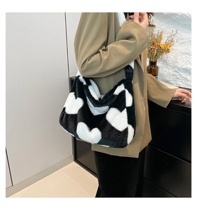 Detail der weichen Plüsch-Schultertasche mit schwarz-weißem Herzmuster an einem Modell