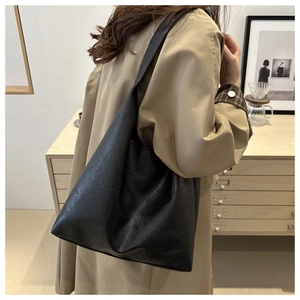 Close-up of minimalist black oversized tote bag worn by a model in a modern interior