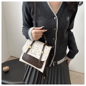 Detailed view of cream and brown crossbody bag with colorful heart patterns and logo