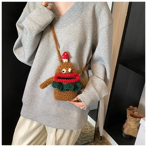Detail of a handmade brown crochet doll crossbody bag worn by a model in casual setting