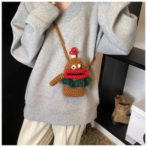 Detail of handmade knit crossbody bag featuring quirky cartoon face and mushroom accent