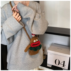 Detail of a brown crochet crossbody bag featuring a quirky face and red lips on a model