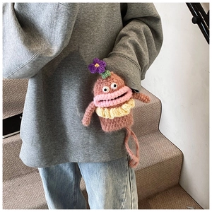 Detail of a handmade crochet monster bag with big eyes and a ruffle scarf on a model