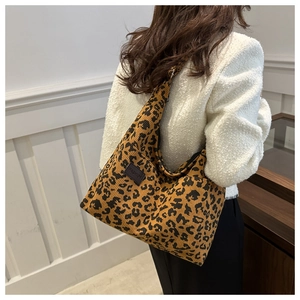 Detailed macro view of leopard print corduroy tote bag featuring a black fashion label
