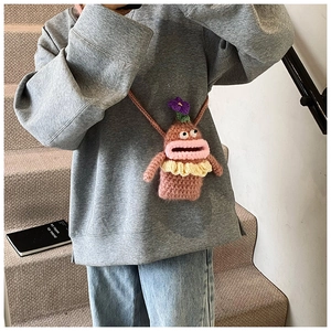 Detail of handmade knitted monster crossbody bag featuring pink lips and purple flower