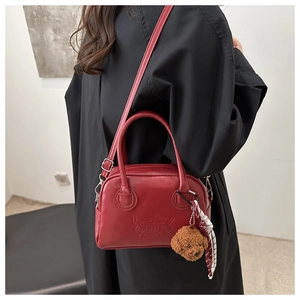 Detail of dark red Boston bag with teddy bear charm and silk scarf on black outfit