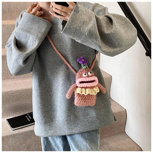Detail of pink handmade crochet doll crossbody bag with big mouth shown on model