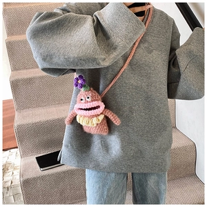 Detail view of a pink knitted monster crossbody bag featuring a big mouth and floral decor