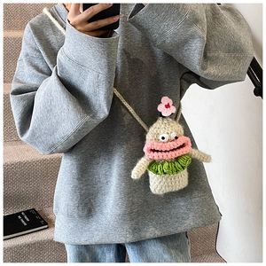 Detail of a handmade crochet monster bag with big lips on a grey sweater outfit