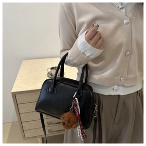 Close-up of black leather handbag with Lucky embossing and plush bear charm