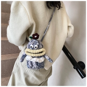 Close-up of a handmade crochet crossbody bag with a funny big mouth and flower detail