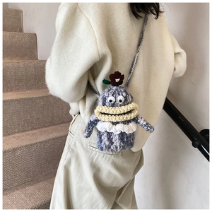 Detail of handmade crochet monster crossbody bag with large eyes and red flower accent