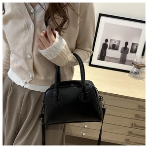 Retro black leather Boston bag with embossed letters shown in an elegant lifestyle setting