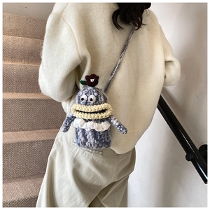 Detail of hand-knitted monster crossbody bag featuring creative big eyes and floral accent