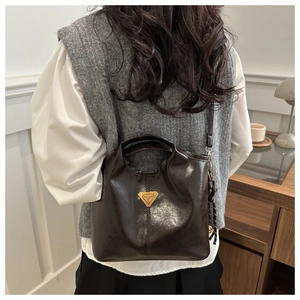 Close-up of a vintage dark brown bucket bag with a golden metal triangular logo plaque
