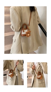 Mini contrast-color shell bag with brown plush bear charm shown on a beige blazer outfit