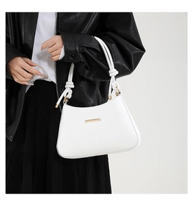 Detail of white faux leather shoulder bag with knot strap and gold metal plate