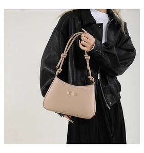 Detail of light beige crescent handbag with knotted strap and gold metal hardware