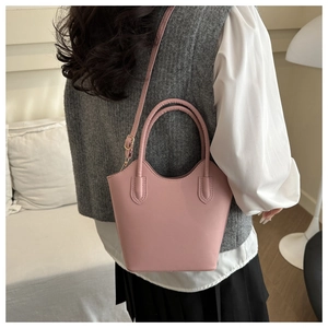 Lifestyle shot of a pale pink bucket bag with top handles and adjustable strap