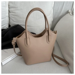 Detail of beige faux leather bucket bag with wavy rim, gold hardware, and long strap