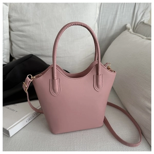 Detail of rose pink bucket bag on sofa with leather texture and gold hardware details