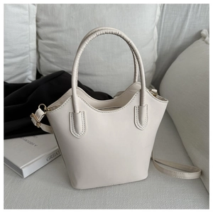 Detailed view of cream PU leather bucket bag with wavy trim and gold metal hardware