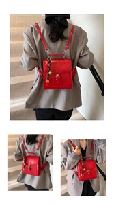 Detail view of red vintage PU leather backpack featuring a decorative bell charm and buckle