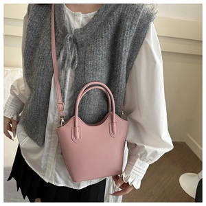 Close-up of pink vegan leather bucket bag with top handle and gold metal buckles