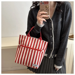 Close-up of red striped canvas tote bag with front zipper pocket and Fashion Instinct label