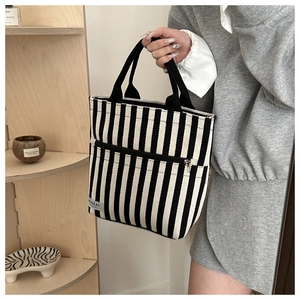 Close-up of black and white striped canvas tote bag with functional front zipper pocket