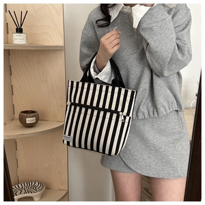 Detail shot of black and white striped canvas tote bag with metal zipper and fabric label